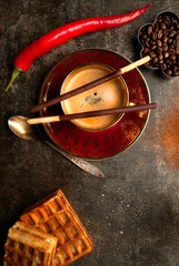 A cup of black coffee and a hot pepper chocolate on a dark background 