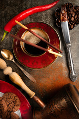 A cup of black coffee and a hot pepper chocolate on a dark background 