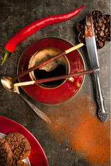 A cup of black coffee and a hot pepper chocolate on a dark background 