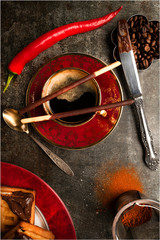 A cup of black coffee and a hot pepper chocolate on a dark background 