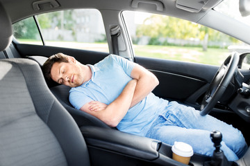 transport, rest and driving concept - tired man or driver sleeping in car