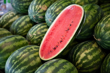 heap of green watermelon and piece of red watermelon fruits in market .