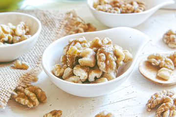 Natural walnuts in bowls on a white wooden table of a rustic kitchen. Sackcloth and wood spoon with empty copy space for Editor's text.