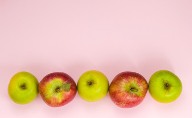 Ripe juicy apples of new crop. Group of different colors apples in line isolated on pink background with copy space for text. Symbol of healthy lifestyle. Fruits rich in vitamins, iron. Organic food. 