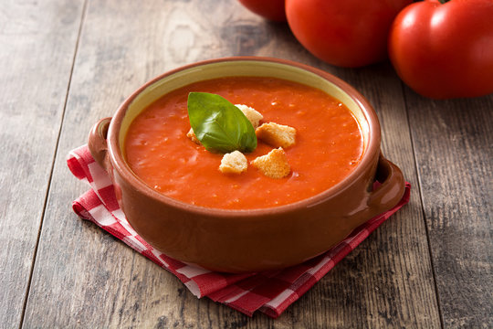 Tomato soup in brown bowl on wooden table