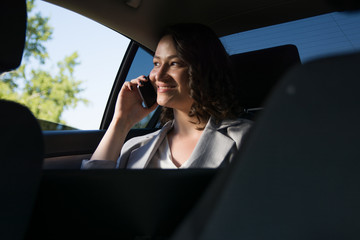 Smiling businesswoman using smart phone in the car