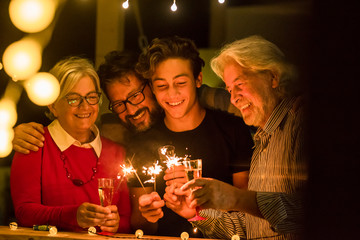 group of two seniors and an adult and a teenager together having fun with sparlers the new year to celebrate - happy family with lights