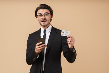 Image of handsome businessman holding cellphone and credit card