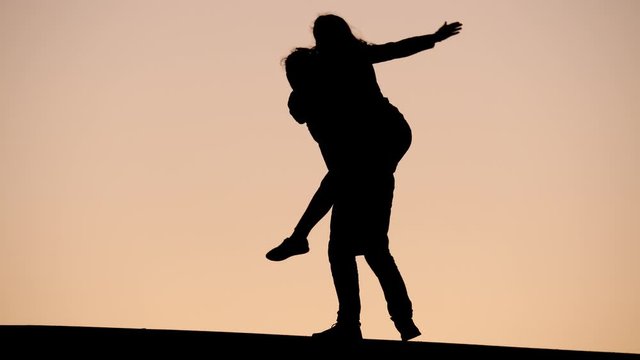 Man carry young woman on back, silhouette run against evening sky. Happy couple spend time together, enjoy nice hours at end of summer day