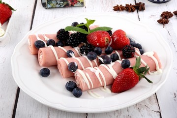 Rolls of canned ham stuffed with cheese served with seasonal fruit. Tasty traditional food