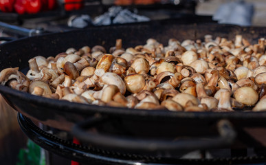 Lots of fried champignons in a large cast-iron skillet in the open air