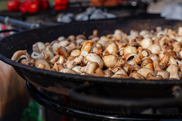 Lots of fried champignons in a large cast-iron skillet in the open air