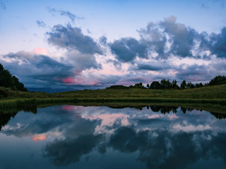 Mirror reflection of clouds on lake or river water surface. Natural background at evening