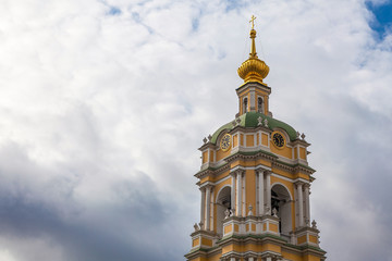 Fototapeta na wymiar The bell tower of the Novospassky Monastery with a clock against a picturesque cloudy sky