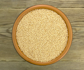 Amaranth seeds in ceramic bowl isolated on wood background.