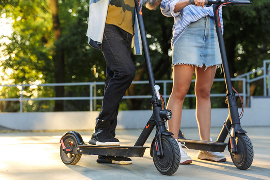 Cropped image of young caucasian couple smiling while riding e-scooters - Powered by Adobe