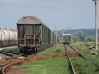 Obraz premium Train standing on siding on a sunny day in summer. Railway freight wagons and tanks of a different type and color.