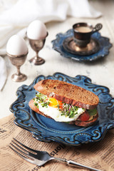 Breakfast with fried egg and rye bread. Sandvia on a blue ceramic plate. Concept of still life and...