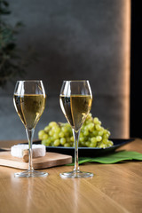 Pouring white wine into the glass above the table set with grape cheese appetizers