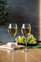 Pouring white wine into the glass above the table set with grape cheese appetizers