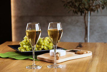 Pouring white wine into the glass above the table set with grape cheese appetizers
