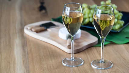 Pouring white wine into the glass above the table set with grape cheese appetizers