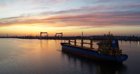 Cargo ship at sunset on the sea. Amazing aerial shot. Sea port