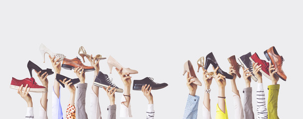 Hands holding different shoes on isolated background - obrazy, fototapety, plakaty