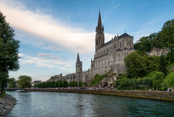 Fototapeta na wymiar Side view of the sanctuary of Our Lady of Lourdes (France), next to the River Ousse, during the sunset.