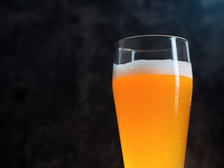 A glass of wheat beer on a dark background close-up with copyspace