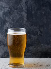 A glass of light beer on a dark background