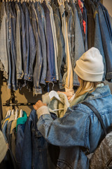 Young girl shopper choosing new clothes at jeans store