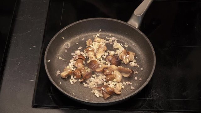 Stir frying mushrooms with garlic and onion. Cooking pasta. Italian cuisine. Above view