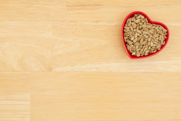 Sunflower seeds in a red bowl for the health benefits of the snack