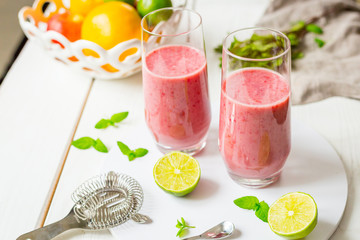 Two Glasses of Smoothie with Berries, Grapefruit, Lemon, Lime and Mint on White Wooden Background, Detox Time