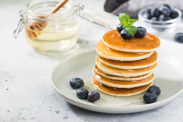 Sweet pancakes with honey and blueberries on the bright kitchen table