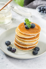 Sweet pancakes with honey and blueberries on the bright kitchen table
