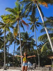woman streching with palm trees on white sand beach at Paliton Beach in Siquijor Island, Philippines.  Tropical  summer vacation concept