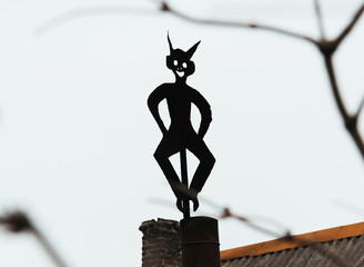 A dash figure made of metal and mounted on a chimney of a building