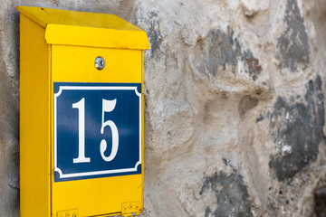 Yellow postbox on stone wall. Mailbox with number 15.