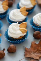 Autumn cupcakes decorated with cream and cookies leaves on gray wooden background. Soft focus. Thanksgiving day or Halloween celebration concept