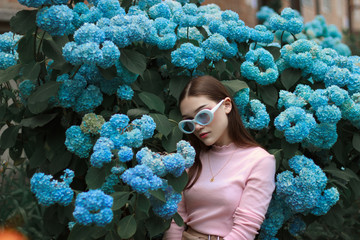Stylish gorgeous young brunette girl with red lips wearing ping t-shirt and white sunglasses,...