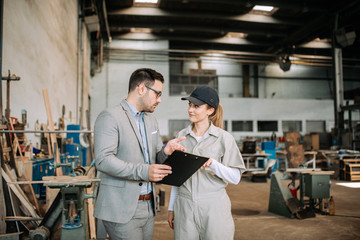 Fototapeta premium Elegant manager talking to a female worker at metalworking shop.