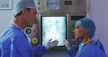 Side view of Multi-ethnic doctors discussing over x-ray report on light box in hospital