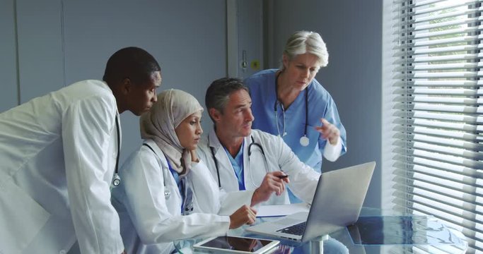 Front view of Multi-ethnic doctors discussing over laptop in hospital