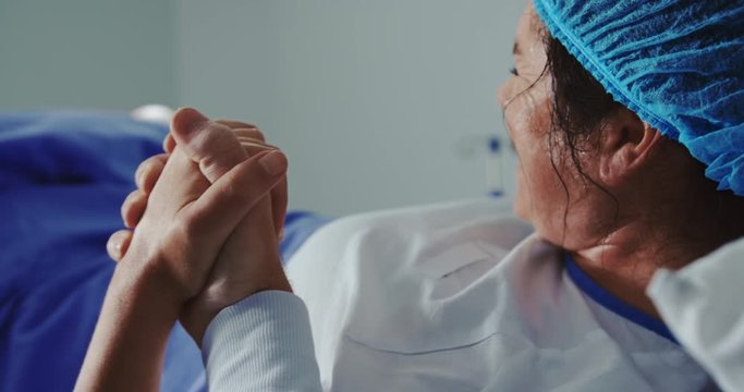 Close-up of man comforting pregnant woman during labor in operation theater at hospital