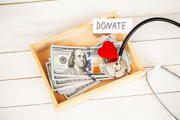 Donate conception. Box with money on white wood background