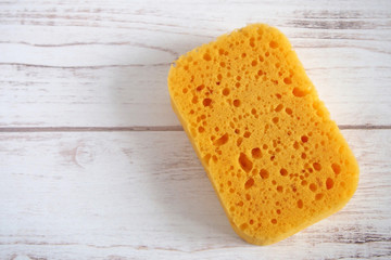 Yellow spongewashcloth on a wooden background. Copy space