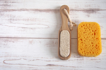 Yellow spongewashcloth with pumice. Self-care items on a wooden background, zero waste concept. Copy space