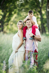 a son sits on his dad's shoulders, and his mom stands near